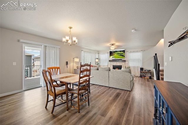 4928 Wolf Moon Dr, Colorado Springs, CO 80911 - dining space with wood finished floors, a fireplace, a chandelier, and a textured ceiling