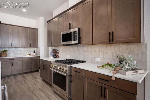17226 Alsike Clover Ct, Monument, CO 80132 - kitchen with stainless steel appliances, backsplash, light countertops, light wood finished floors, and dark brown cabinetry