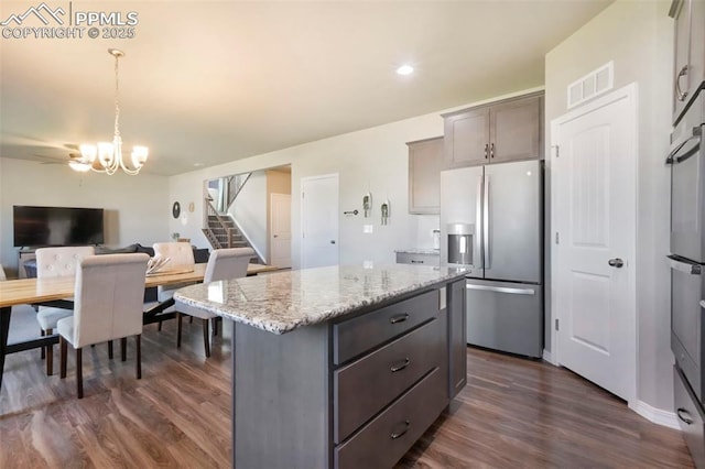4631 Zircon Dr, Colorado Springs, CO 80938 - kitchen featuring stainless steel refrigerator with ice dispenser, dark wood-style floors, a chandelier, light stone counters, and decorative light fixtures