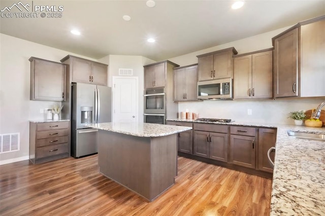4631 Zircon Dr, Colorado Springs, CO 80938 - kitchen with appliances with stainless steel finishes, a kitchen island, light wood-type flooring, light stone countertops, and recessed lighting