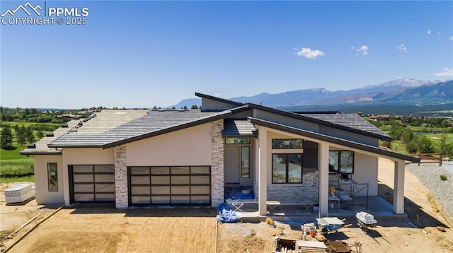 13497 Pride Mountain Dr, Colorado Springs, CO 80921 - contemporary home featuring a mountain view, dirt driveway, an attached garage, and a tile roof