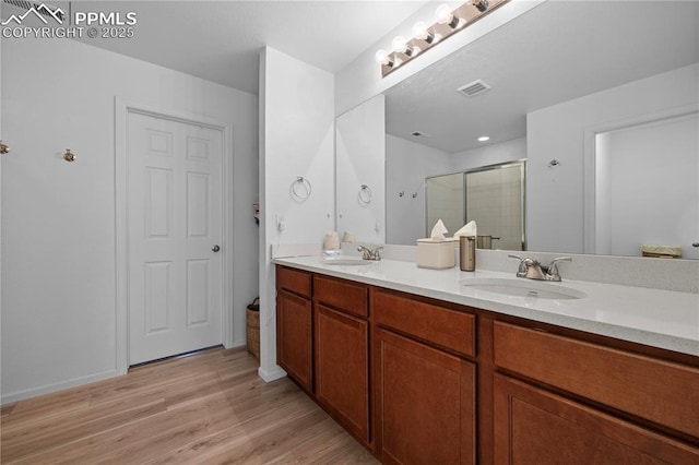 6131 Vickie Ln, Colorado Springs, CO 80923 - full bath with double vanity, a stall shower, and wood finished floors