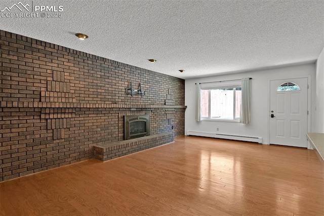 3710 Saddle Rock Rd, Colorado Springs, CO 80918 - unfurnished living room with a baseboard heating unit, a textured ceiling, brick wall, wood finished floors, and a brick fireplace
