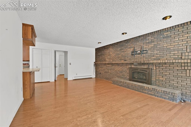 3710 Saddle Rock Rd, Colorado Springs, CO 80918 - unfurnished living room featuring a baseboard heating unit, a textured ceiling, wood finished floors, a brick fireplace, and brick wall