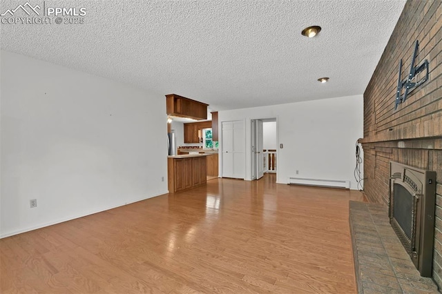 3710 Saddle Rock Rd, Colorado Springs, CO 80918 - unfurnished living room with a baseboard heating unit, a textured ceiling, a fireplace, and wood finished floors