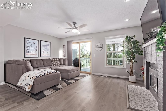 12183 W Chenango Dr, Morrison, CO 80465 - living room featuring wood finished floors, a ceiling fan, a textured ceiling, a brick fireplace, and recessed lighting
