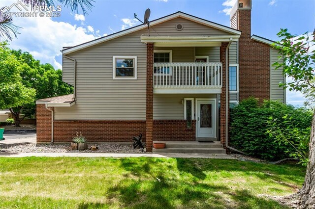 12183 W Chenango Dr, Morrison, CO 80465 - back of house featuring a balcony, brick siding, a lawn, and a chimney