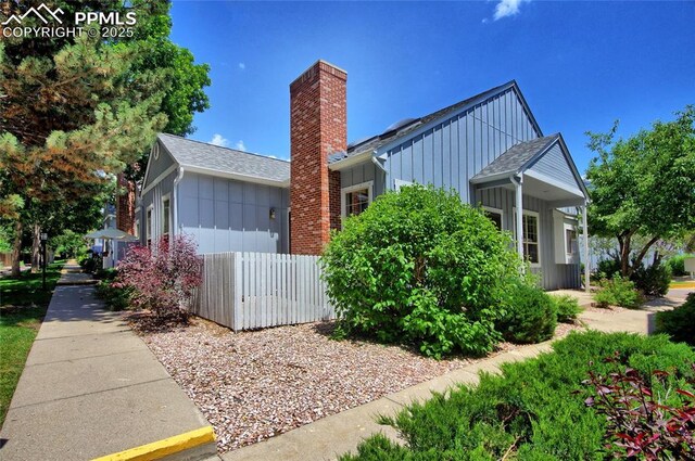 6872 Los Reyes Cir, Colorado Springs, CO 80918 - view of property exterior featuring board and batten siding, a chimney, and roof with shingles