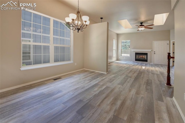 6872 Los Reyes Cir, Colorado Springs, CO 80918 - unfurnished living room featuring a skylight, wood finished floors, ceiling fan, a glass covered fireplace, and a chandelier