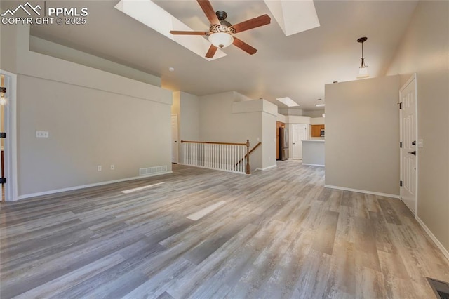 6872 Los Reyes Cir, Colorado Springs, CO 80918 - unfurnished living room featuring a ceiling fan, a skylight, and light wood finished floors