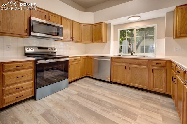 6872 Los Reyes Cir, Colorado Springs, CO 80918 - kitchen featuring appliances with stainless steel finishes, light wood-style flooring, backsplash, light countertops, and brown cabinetry
