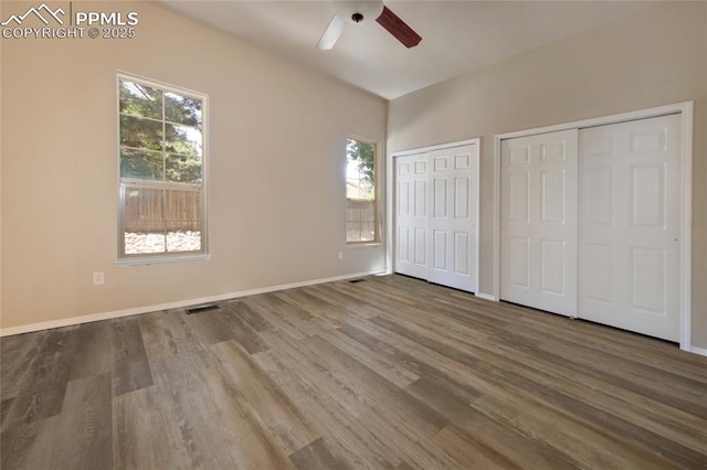 6872 Los Reyes Cir, Colorado Springs, CO 80918 - unfurnished bedroom featuring multiple closets, wood finished floors, multiple windows, and a ceiling fan