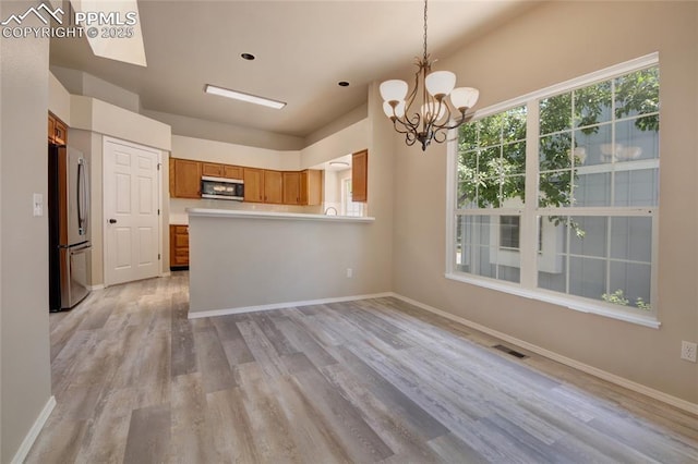6872 Los Reyes Cir, Colorado Springs, CO 80918 - kitchen with stainless steel appliances, a chandelier, brown cabinets, light wood-style floors, and light countertops