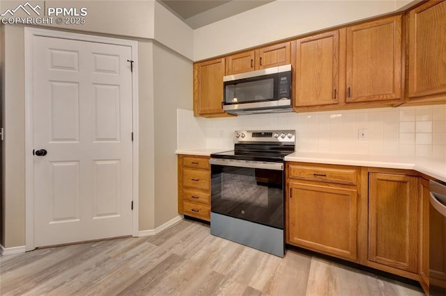 6872 Los Reyes Cir, Colorado Springs, CO 80918 - kitchen featuring appliances with stainless steel finishes, light wood-type flooring, and brown cabinets