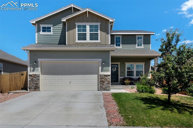 2823 Gobi Dr, Colorado Springs, CO 80939 - view of front of house featuring a garage, driveway, stone siding, and covered porch