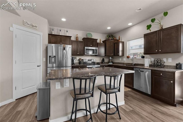 2823 Gobi Dr, Colorado Springs, CO 80939 - kitchen featuring stainless steel appliances, a kitchen island, dark brown cabinetry, light wood-style floors, and a breakfast bar