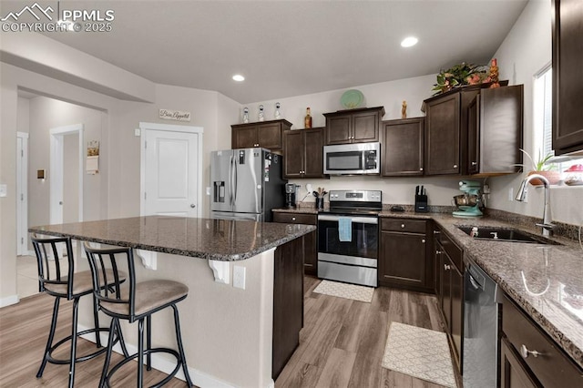 2823 Gobi Dr, Colorado Springs, CO 80939 - kitchen with stainless steel appliances, light wood-style floors, a kitchen bar, dark brown cabinets, and a center island
