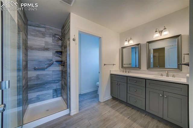 6604 Watusi Rd, Peyton, CO 80831 - bathroom with double vanity, a stall shower, and wood finished floors