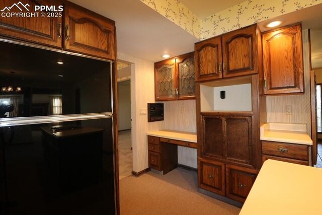 4170 Broadmoor Bluffs Dr, Colorado Springs, CO 80906 - kitchen with wallpapered walls, built in desk, fridge, light carpet, and light countertops