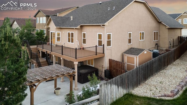 10489 Cedar Breaks Dr, Peyton, CO 80831 - rear view of house featuring stucco siding, a covered hot tub, a deck, a shingled roof, and a patio area
