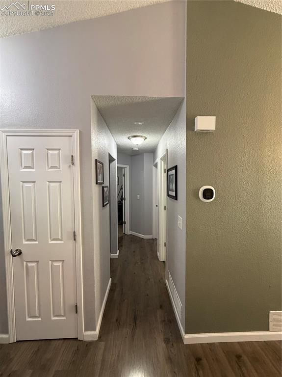 5926 Wisteria Dr, Colorado Springs, CO 80919 - hallway featuring dark wood-type flooring and a textured wall