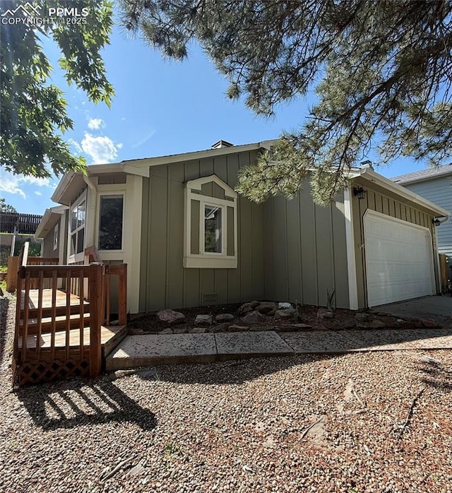 5926 Wisteria Dr, Colorado Springs, CO 80919 - view of property exterior with board and batten siding, an attached garage, and driveway