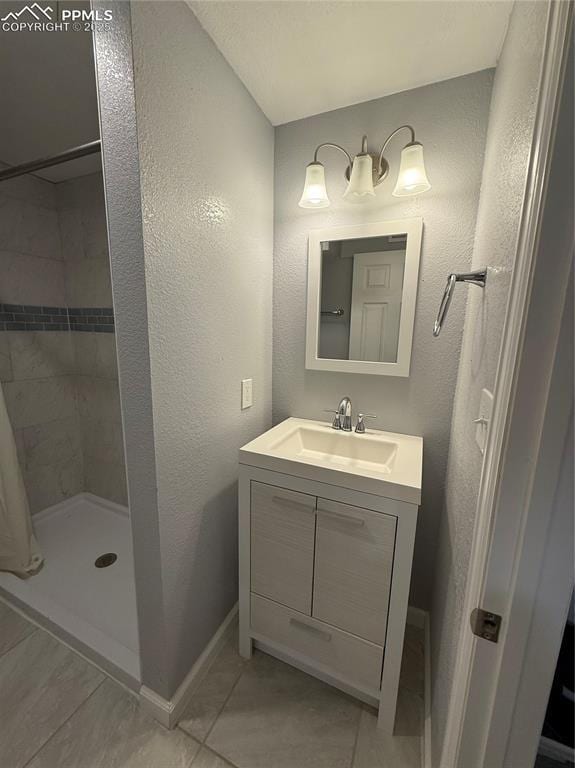 5926 Wisteria Dr, Colorado Springs, CO 80919 - bathroom with vanity, a tile shower, tile patterned floors, and a textured wall