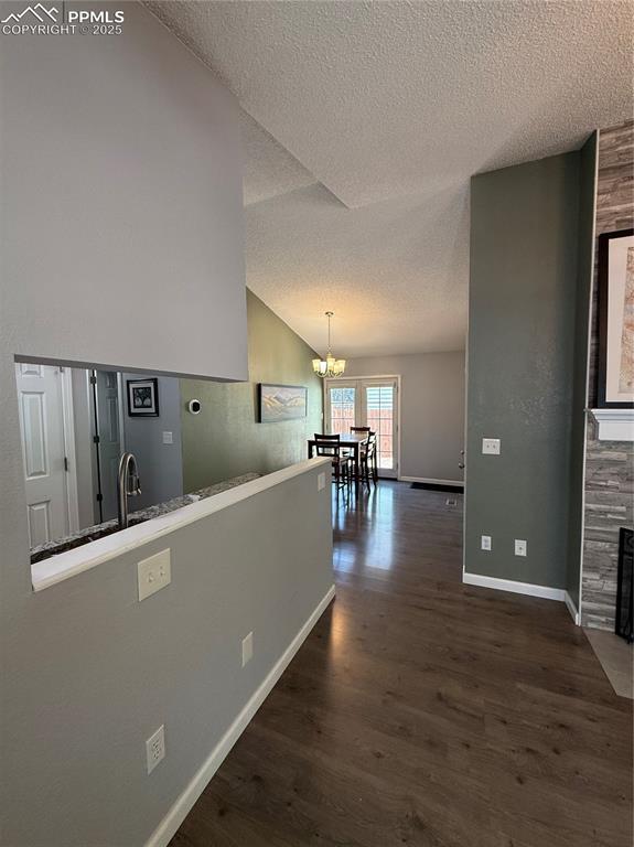 5926 Wisteria Dr, Colorado Springs, CO 80919 - hall with a textured ceiling, dark wood-style floors, a chandelier, and vaulted ceiling