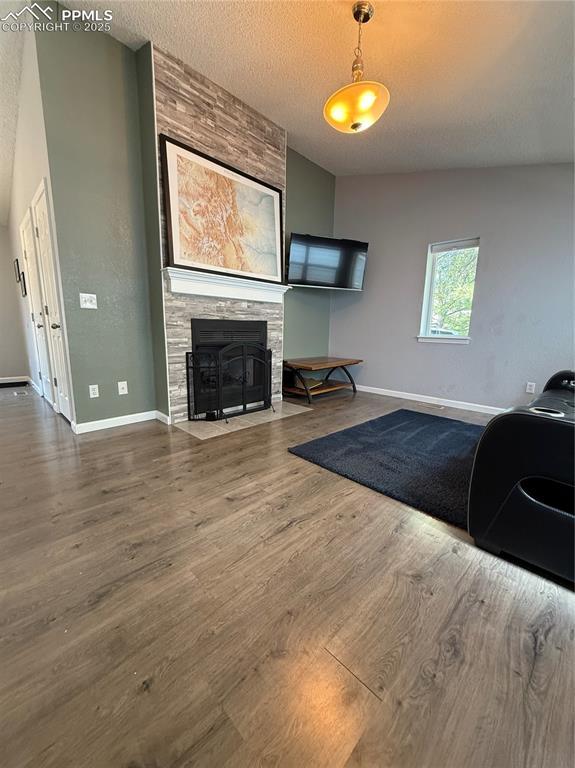 5926 Wisteria Dr, Colorado Springs, CO 80919 - living area featuring wood finished floors, a stone fireplace, and a textured ceiling