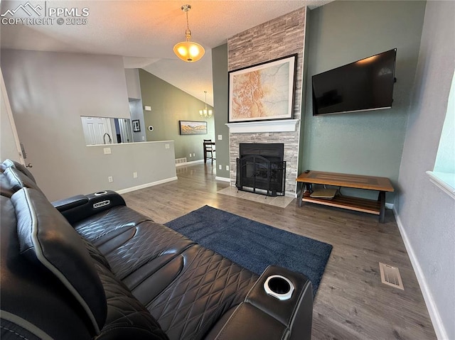 5926 Wisteria Dr, Colorado Springs, CO 80919 - living room with vaulted ceiling, wood finished floors, a chandelier, and a stone fireplace