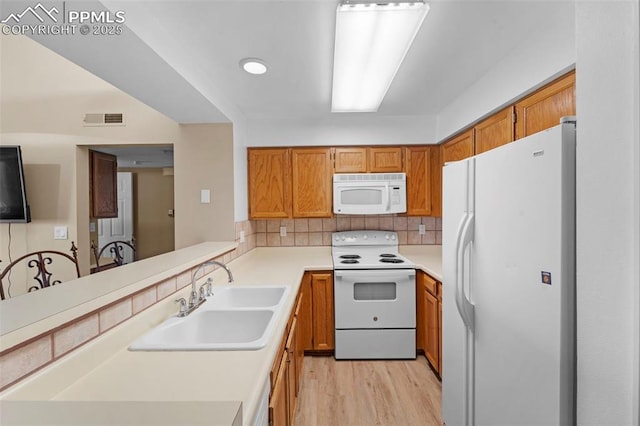 3692 Iguana Dr, Colorado Springs, CO 80910 - kitchen featuring white appliances, light wood finished floors, brown cabinetry, tasteful backsplash, and light countertops