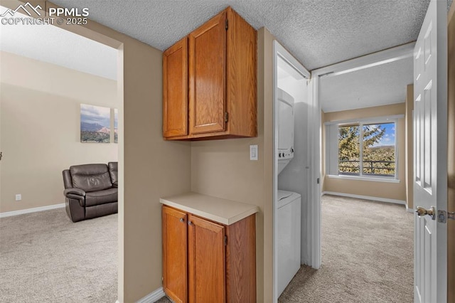 3692 Iguana Dr, Colorado Springs, CO 80910 - hallway with stacked washing machine and dryer, light colored carpet, and a textured ceiling
