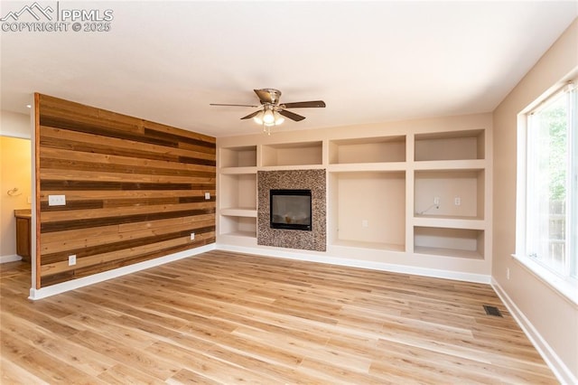 7292 Gardenstone Dr, Colorado Springs, CO 80922 - unfurnished living room featuring a ceiling fan, built in features, light wood-style floors, and a tiled fireplace