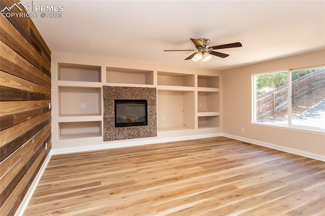 7292 Gardenstone Dr, Colorado Springs, CO 80922 - unfurnished living room featuring light wood-style flooring, built in features, a tile fireplace, and a ceiling fan