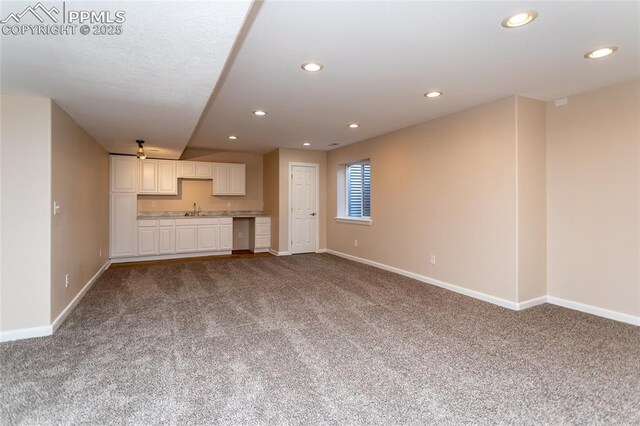 7292 Gardenstone Dr, Colorado Springs, CO 80922 - unfurnished living room featuring carpet, bar with sink, and recessed lighting