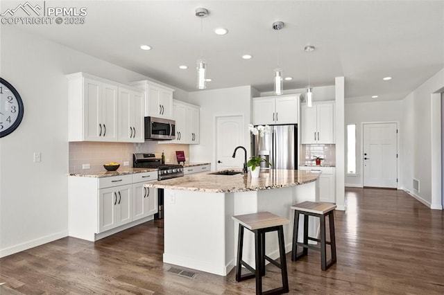 8309 Tom Ketchum Dr, Colorado Springs, CO 80908 - kitchen with stainless steel appliances, decorative backsplash, a breakfast bar, white cabinets, and recessed lighting