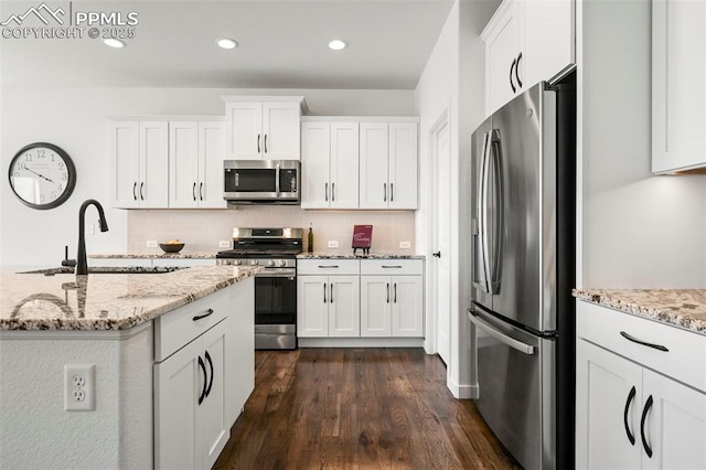 8309 Tom Ketchum Dr, Colorado Springs, CO 80908 - kitchen featuring stainless steel appliances, dark wood-style floors, white cabinetry, decorative backsplash, and recessed lighting