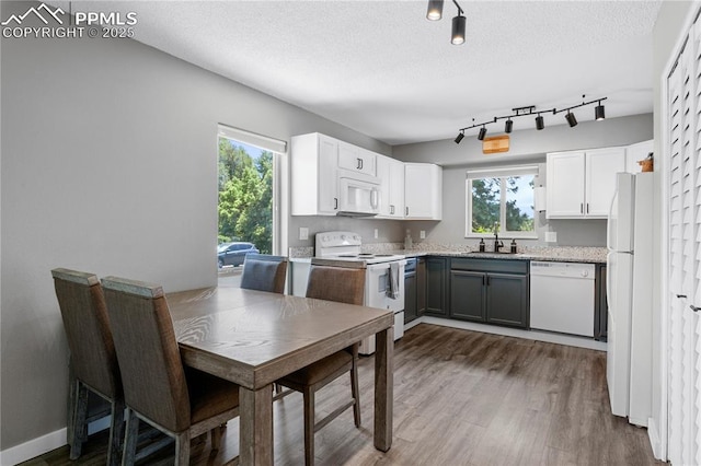 4742 Villa Cir Unit A, Colorado Springs, CO 80918 - kitchen featuring white appliances, dark wood-type flooring, healthy amount of natural light, white cabinets, and a textured ceiling