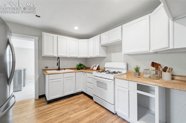109 S 24th St, Colorado Springs, CO 80904 - kitchen featuring white range with gas stovetop, freestanding refrigerator, light countertops, light wood-type flooring, and white cabinetry