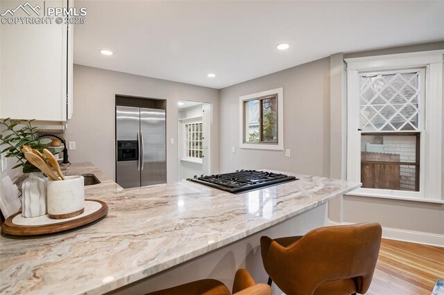 122 E Jefferson St, Colorado Springs, CO 80907 - kitchen featuring built in fridge, black gas cooktop, light stone counters, wood finished floors, and a peninsula