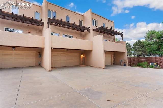 3219 W Pikes Peak Ave, Colorado Springs, CO 80904 - view of front of house with stucco siding, an attached garage, a pergola, and concrete driveway