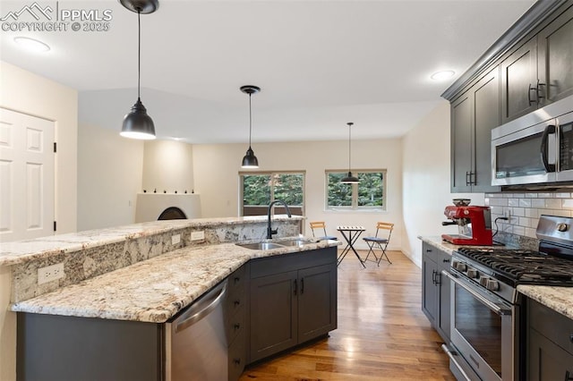 3219 W Pikes Peak Ave, Colorado Springs, CO 80904 - kitchen with stainless steel appliances, light wood-type flooring, tasteful backsplash, light stone countertops, and hanging light fixtures