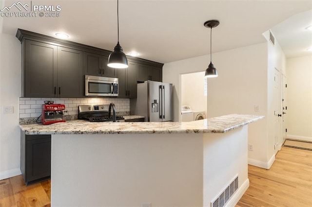 3219 W Pikes Peak Ave, Colorado Springs, CO 80904 - kitchen featuring appliances with stainless steel finishes, washing machine and clothes dryer, decorative backsplash, and light wood-type flooring