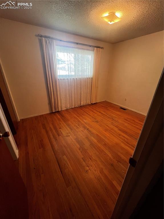 135 Judson St, Colorado Springs, CO 80911 - empty room featuring wood finished floors and a textured ceiling