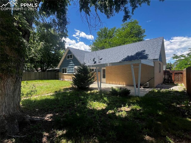135 Judson St, Colorado Springs, CO 80911 - back of house with a shingled roof, a patio area, a fenced backyard, and brick siding