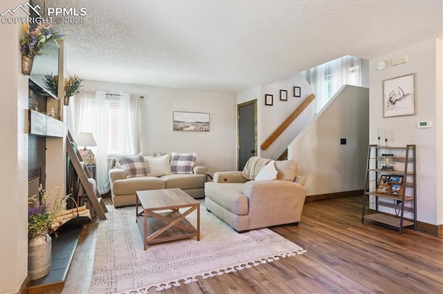 2722 Front Royal Dr, Colorado Springs, CO 80919 - living area featuring a textured ceiling, wood finished floors, stairs, and a glass covered fireplace