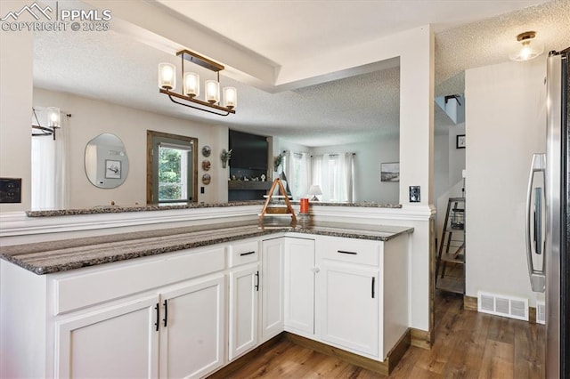 2722 Front Royal Dr, Colorado Springs, CO 80919 - kitchen with a textured ceiling, white cabinets, dark wood-style flooring, dark stone counters, and fridge