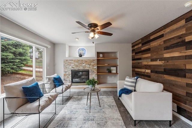 1410 Almagre Peak Dr, Colorado Springs, CO 80921 - living area featuring wooden walls, ceiling fan, and a fireplace