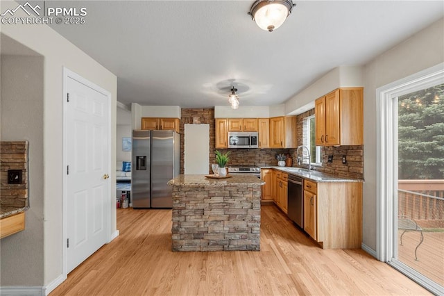 1410 Almagre Peak Dr, Colorado Springs, CO 80921 - kitchen with appliances with stainless steel finishes, light wood finished floors, decorative backsplash, a kitchen island, and light stone counters
