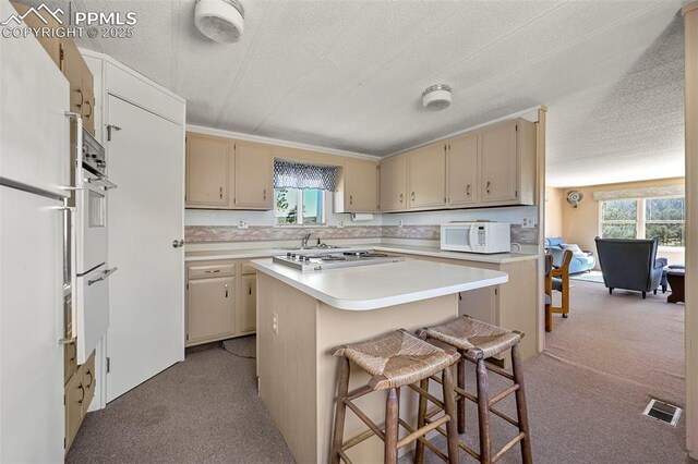 332 Valley Cir, Guffey, CO 80816 - kitchen with white microwave, light carpet, cooktop, cream cabinetry, and a textured ceiling